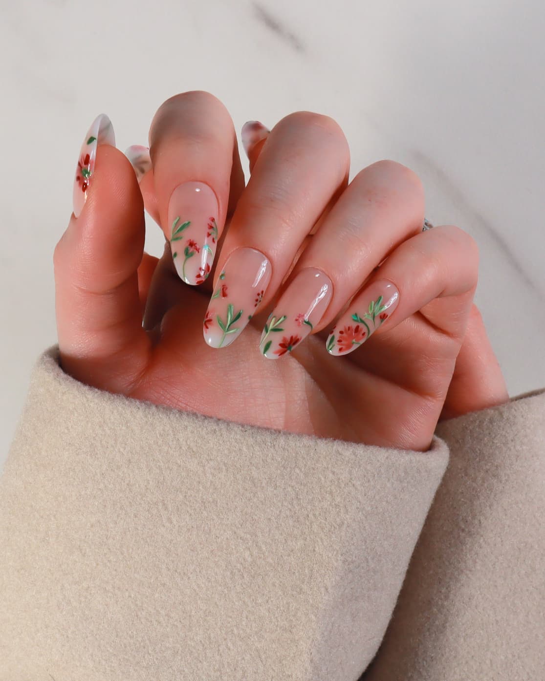 Hand with floral nail design on a neutral background