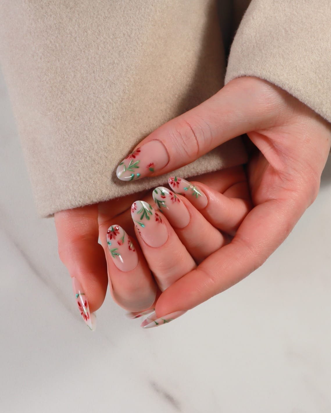Close-up of a hand with floral nail design against a neutral background